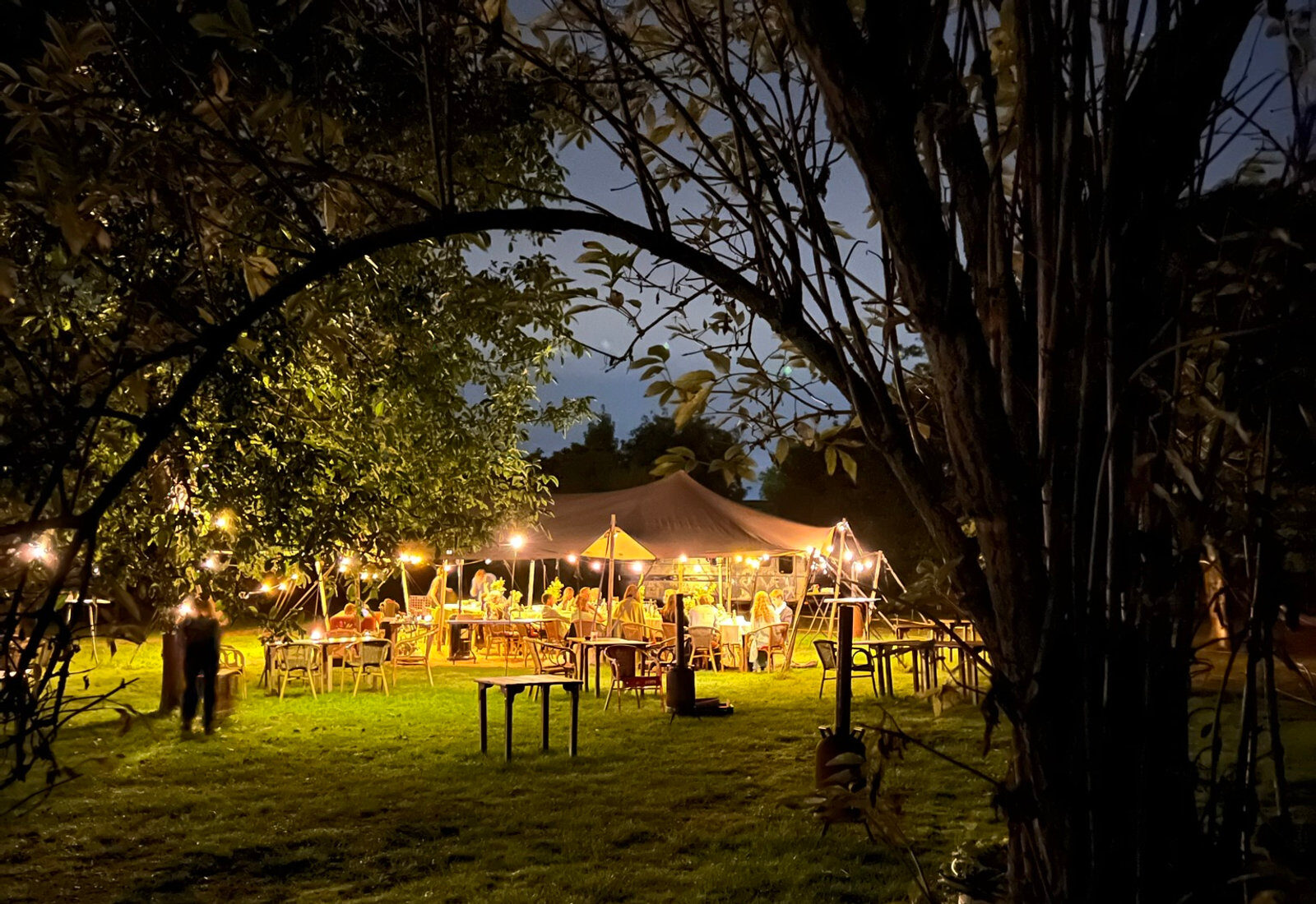 De tuin van Restaurant Oud Vuren bij avond, met verlichte tent onder de bomen